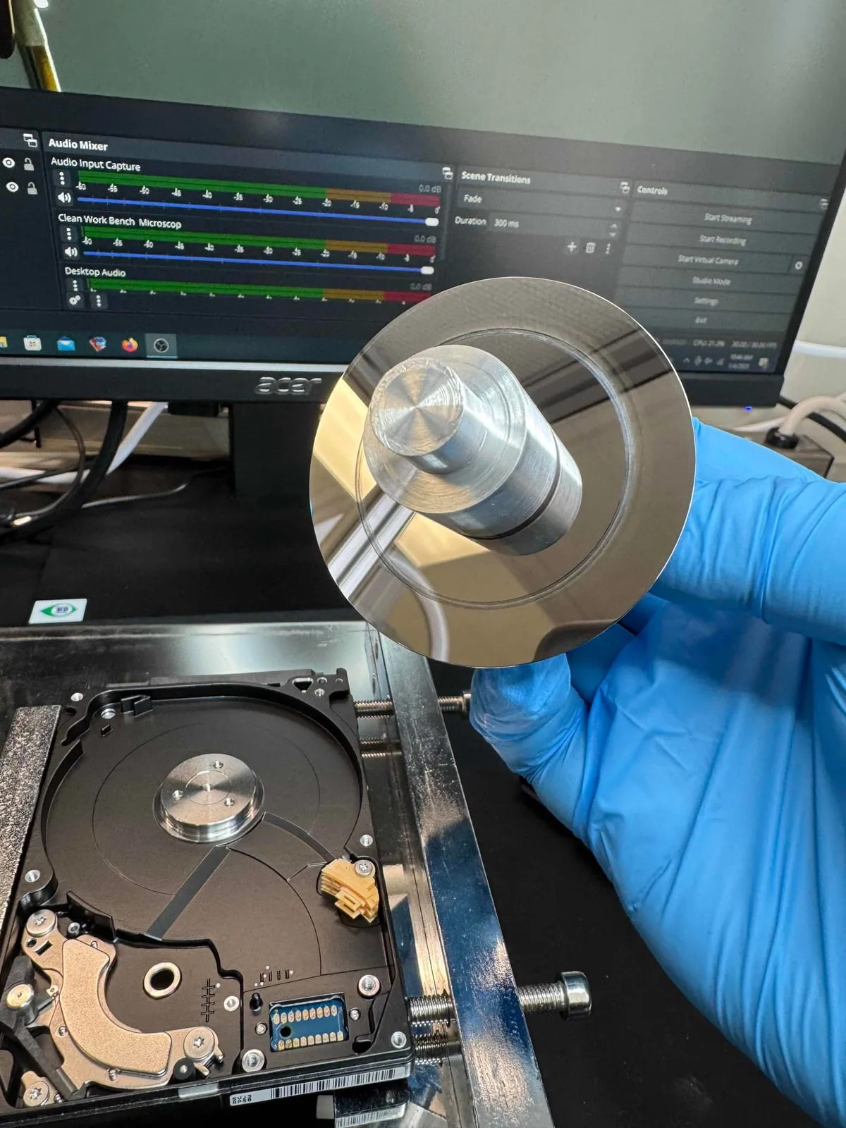 Technician inspecting a failed hard drive platter during controlled mechanical recovery work